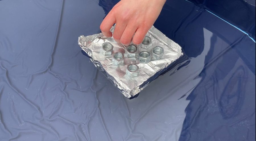 A square "boat" made out of aluminum foil, supporting 8 screw nuts
